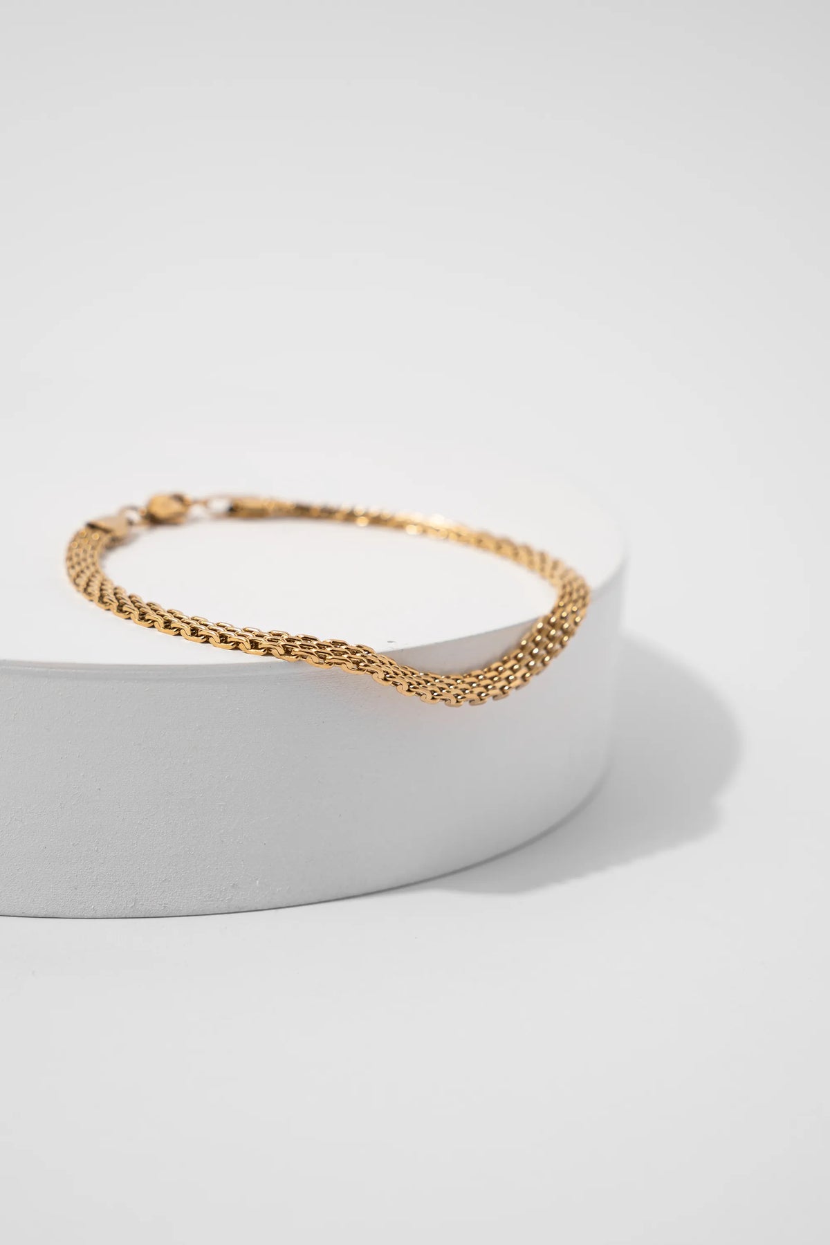 Pulsera Chinesca Gold Impetu Men - pulsera sobre prop redondo blanco fondo blanco vista lateral