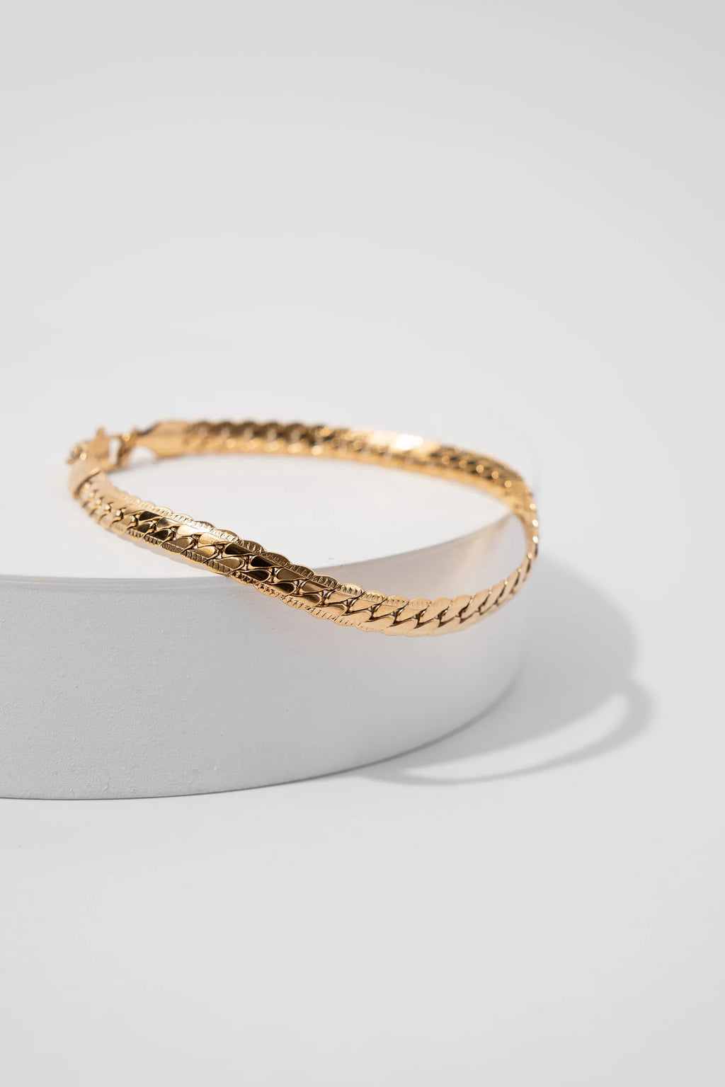 Pulsera Grabada Gold Impetu Men - pulsera sobre prop cilíndrico blanco fondo blanco vista lateral