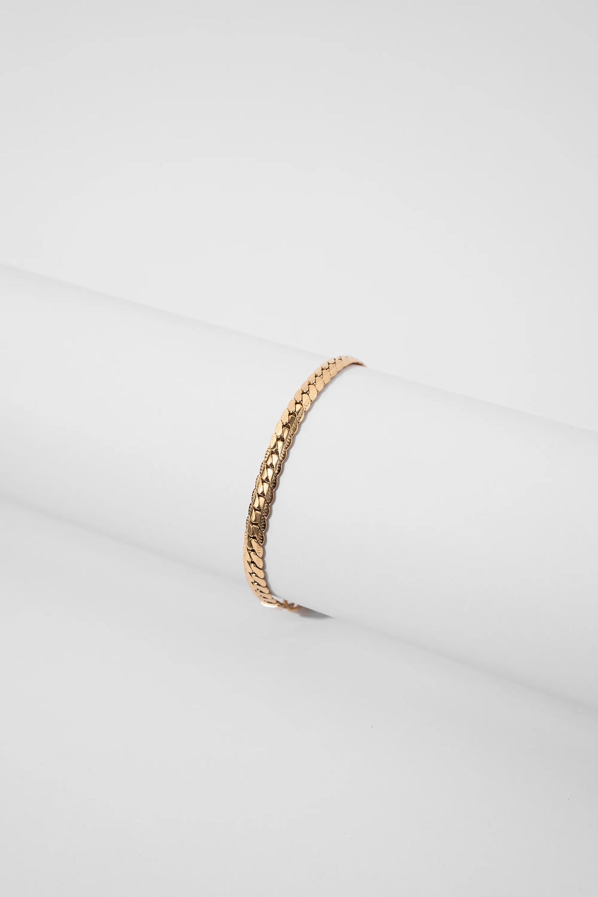 Pulsera Grabada Gold Impetu Men - pulsera sobre prop cilíndrico blanco fondo blanco vista frontal